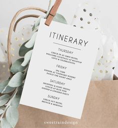 a white sign that reads itinerary hanging from a brown paper bag with greenery