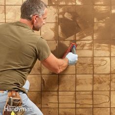 a man painting a wall with brown tiles