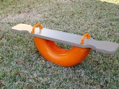 an orange tire swing in the grass with two handles on one end and another handle on the other side