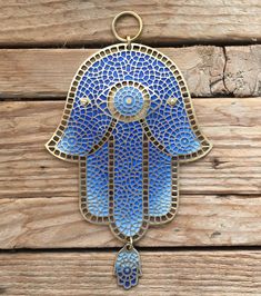 a blue hamsa hanging on a wooden wall