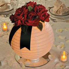 a vase filled with red roses sitting on top of a table next to lit candles