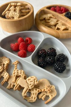 three trays filled with different types of cookies and raspberries next to each other