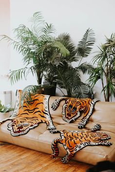 a couch with tiger pillows on it in front of some potted plants and palm trees