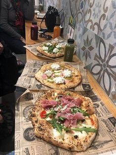 three pizzas sitting on top of cardboard boxes next to each other with toppings