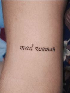 the word mad woman written in cursive font on someone's lower leg