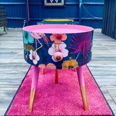 a pink and blue table with flowers painted on the top, sitting on a rug