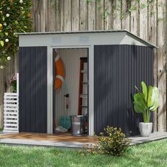 a small shed sitting in the grass next to a wooden fence and potted plant