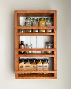 two wooden shelves filled with jars and spices on top of each other in front of a white wall