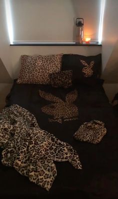 a leopard print comforter on a bed in a room with two candles and pillows