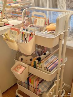 a white cart filled with lots of books next to a window