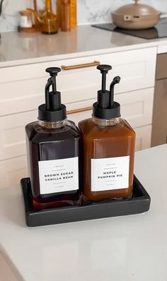 two soap dispensers sitting on top of a white counter in a kitchen