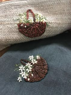 two purses with flowers on them sitting next to each other in front of a pillow