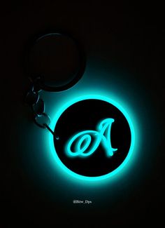 an illuminated keychain with the letter a on it's side in blue light