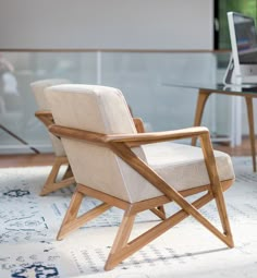 a chair sitting on top of a rug in front of a glass table with a laptop