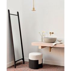 a white sink sitting next to a mirror and a black stand with a bowl on it