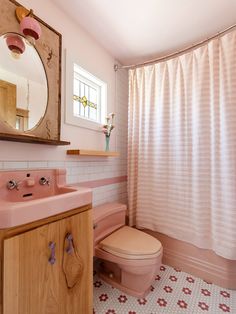 a bathroom with a pink toilet and sink next to a shower curtain in the corner