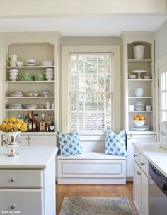 a kitchen with white cabinets and shelves filled with dishes