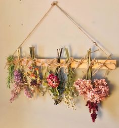 dried flowers hang from a rope on a wall