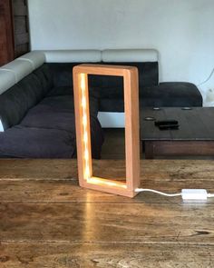 a wooden frame sitting on top of a table next to a light that is plugged in