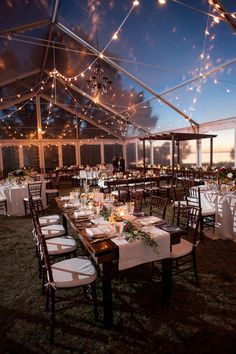 an outdoor tent with tables and chairs set up for a wedding reception at night time