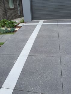 an empty driveway in front of a house with a garage door on the right side