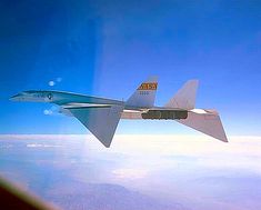 an airplane is flying in the sky above the clouds and land below it, as seen from another plane's window