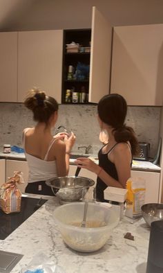 two women are in the kitchen mixing together something with a whisk on her face