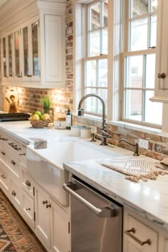 a kitchen with white cabinets and marble counter tops is pictured in this image, there are two windows that look out onto the street