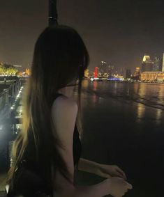 a woman looking out over the water at night