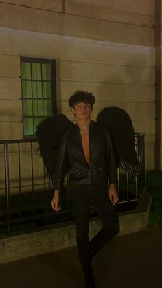 a man in black leather jacket standing next to an angel wing