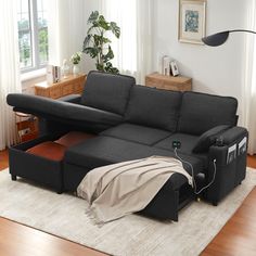 a couch with a pull out bed underneath it in a living room next to a window