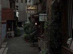 an alley way with signs and plants growing on the side of buildings in tokyo, japan