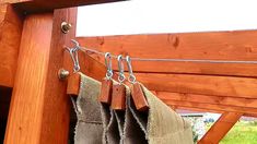 two pieces of cloth hanging on a clothes line with hooks attached to the side of a wooden structure