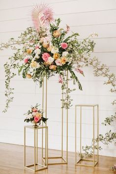 two gold plant stands with flowers on them