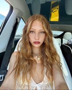 a woman sitting in the back seat of a car looking at the camera with an intense look on her face