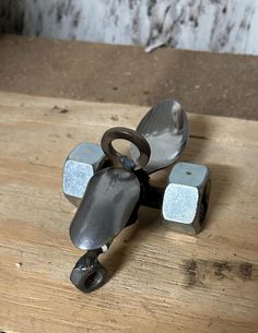 a metal object sitting on top of a wooden table next to a hammer and nut