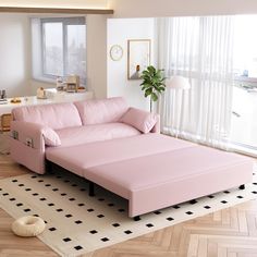 a pink couch sitting on top of a hard wood floor next to a large window