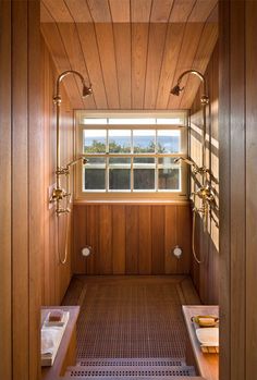 the inside of a bathroom with wood paneling and wooden walls, along with two windows