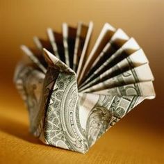 an origami fan made out of one hundred dollar bills sitting on a table