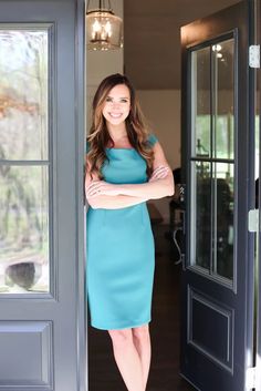 a woman standing in front of a door with her arms crossed