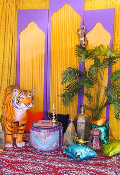 a tiger statue sitting on top of a rug next to a table covered in pillows