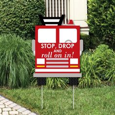 a red fire truck yard sign sitting in the grass next to a bush and shrubbery