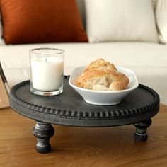 a bowl of bread and a glass of milk sit on a table in front of a couch