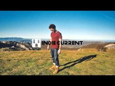 a man standing on top of a grass covered field next to mountains with the words india current