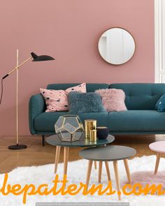 a living room with pink walls, blue couch and white fur rugs on the floor