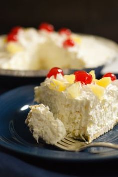 a piece of cake with pineapples and cherries is on a blue plate