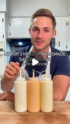 the man is making homemade sauces for his kitchen counter top, and he has three bottles in front of him