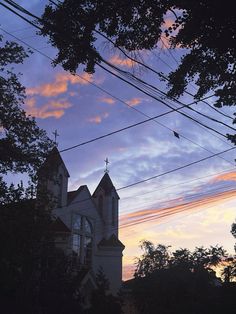 a church steeple is silhouetted against the evening sky with power lines in the foreground