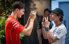 two young men standing next to each other holding up their hands in front of them