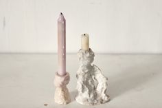 a candle holder with a small white dog next to it and a smaller pink candle